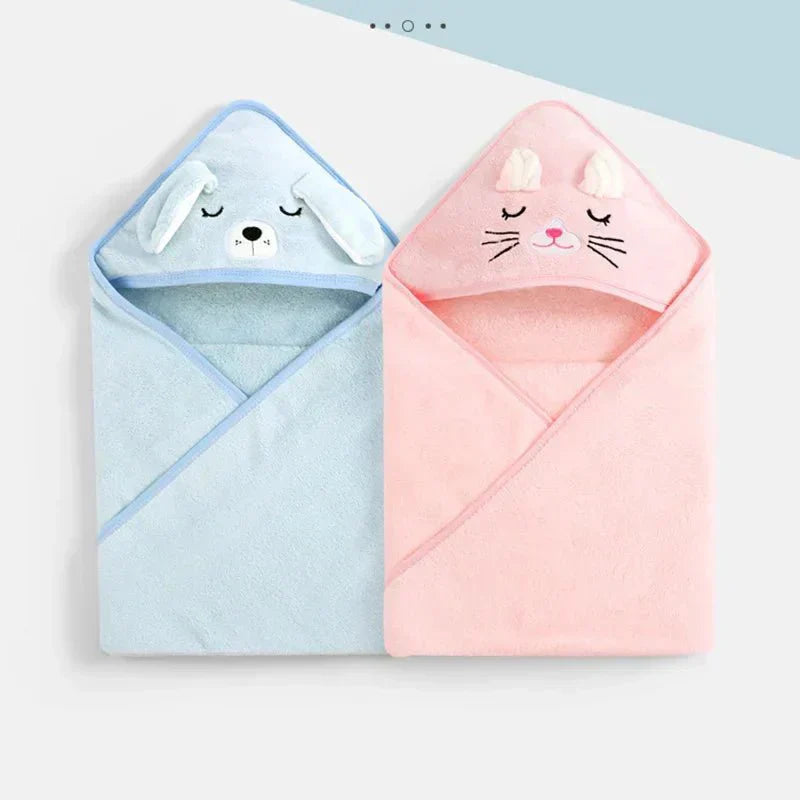 Two baby hooded towels, one blue with a bear design and one pink with a cat design, on a light blue background.